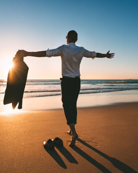 Das Leben ist schön. Mann mit offenen Armen genießt das Leben und die Freiheit am Strand mit Sonnenuntergang