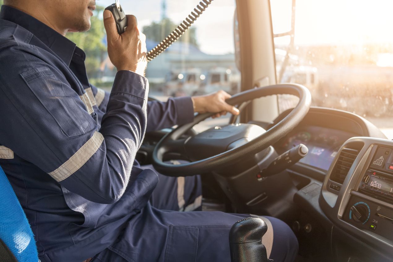 Berufskraftfahrer im Führerhaus eines Lkw, der während der Fahrt moderne Kommunikationssysteme nutzt, geschult durch CZV Kurse