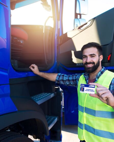 Berufskraftfahrer hält sein Zertifikat nach Abschluss eines CZV Kurses neben seinem Lkw stolz in die Kamera