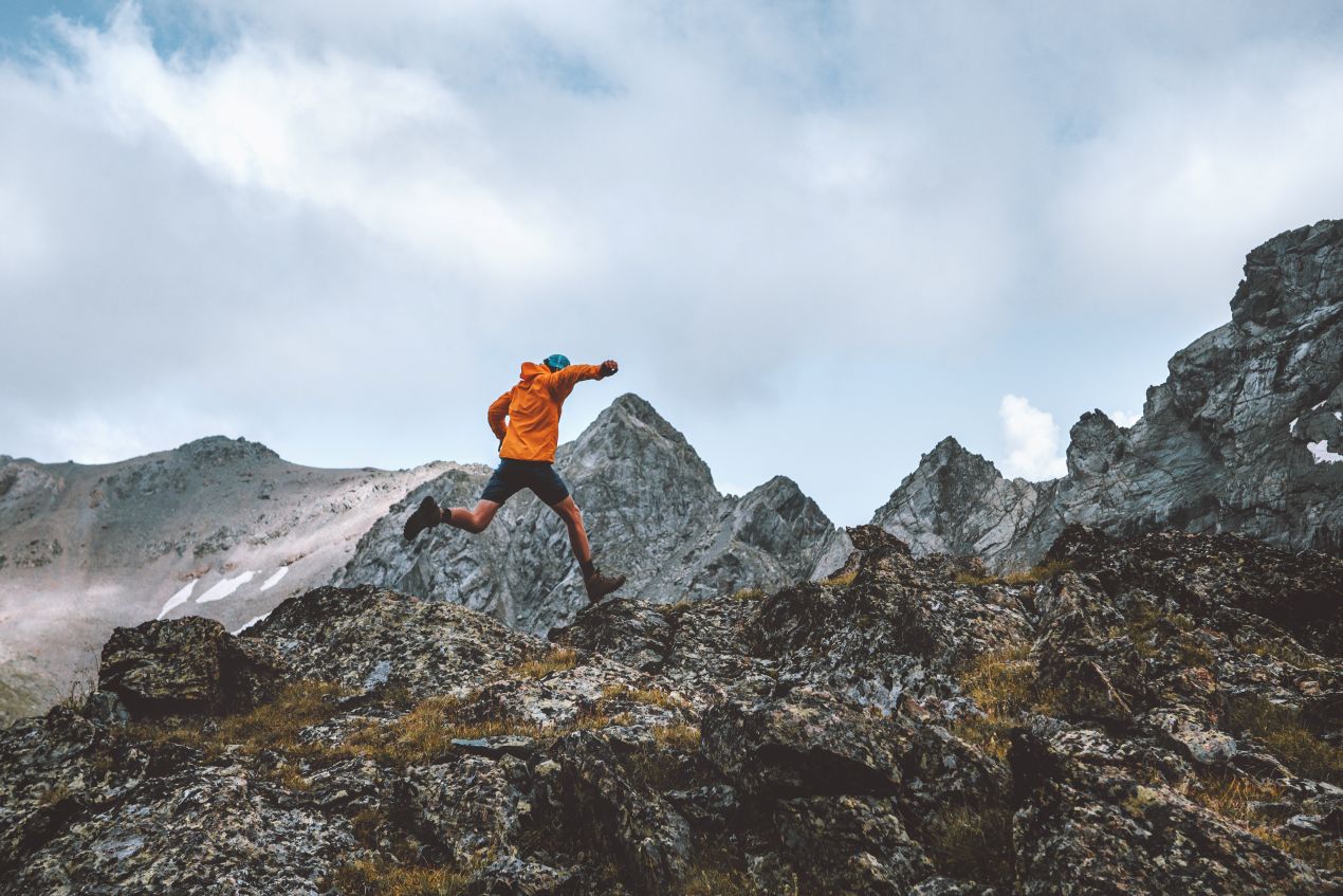 Wanderer in den Bergen, der über Felsen springt, symbolisiert Training und Abenteuer der Besteigung des Kilimandscharo